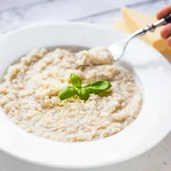 Kremowe risotto z parmezanem i bazylią, idealne do przygotowania w domu. Dowiedz się, jak ugotować ryż do risotto.