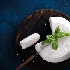 Świeży ser, idealny jako zamiennik ricotty, z bazylią na drewnianej desce.