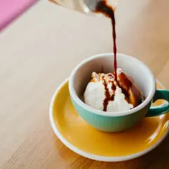 Gorące espresso zalewa kulkę lodów waniliowych w filiżance. Klasyczne lody po włosku, idealne na deser.