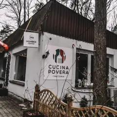 Biały budynek z logo "Cucina Povera - Trattoria" i szyldem "Number Coffee" w otoczeniu drzew.
