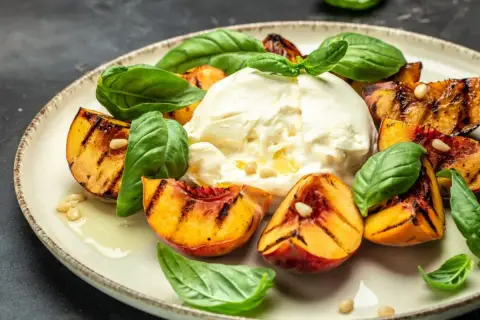 Pyszny **burrata przepis** z grillowanymi brzoskwiniami, świeżą bazylią i orzeszkami pinii. Idealna letnia przekąska.