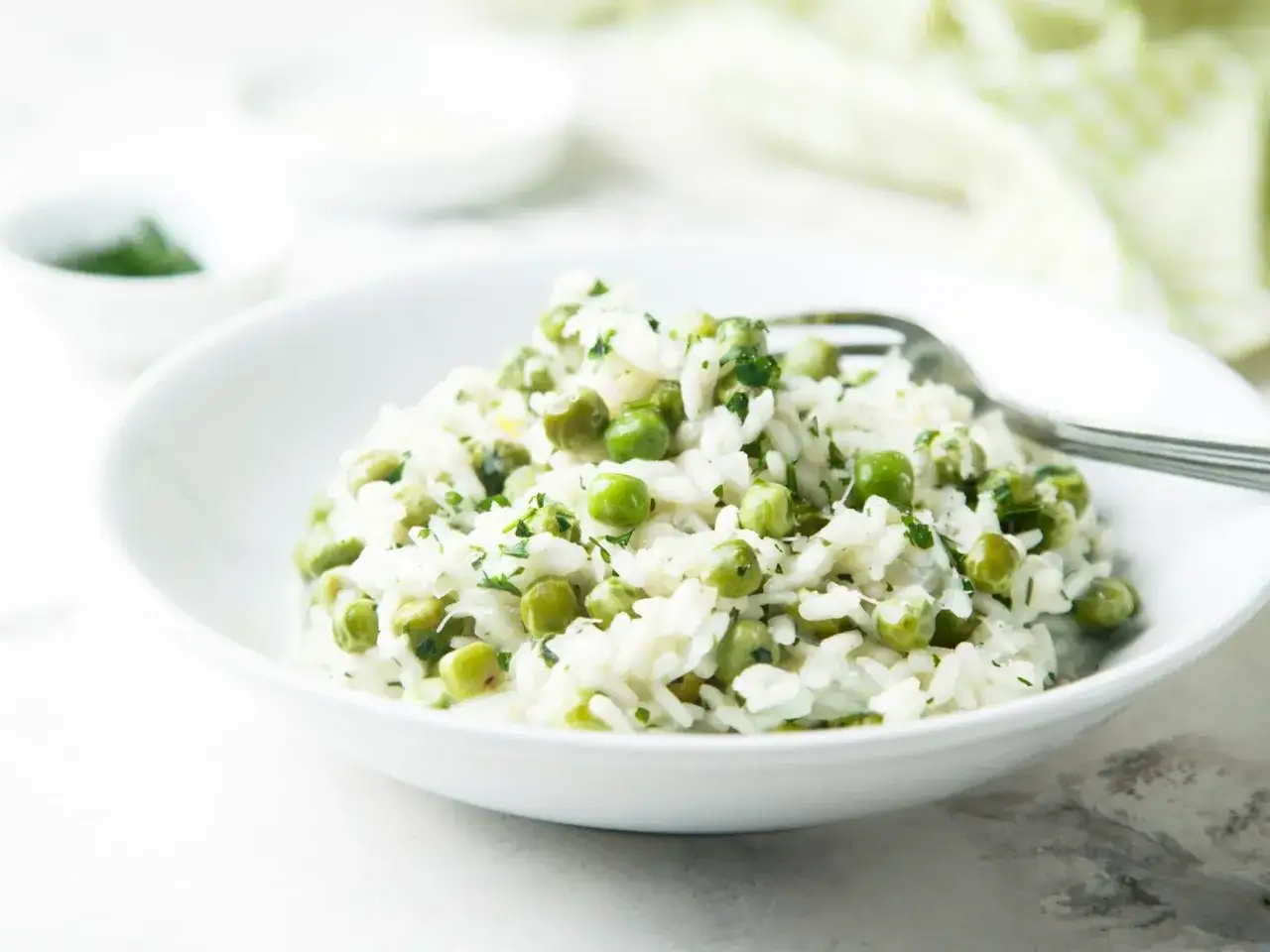 Pyszne risi e bisi, kremowe risotto z groszkiem i ziołami, podane w białej misce, gotowe do jedzenia.