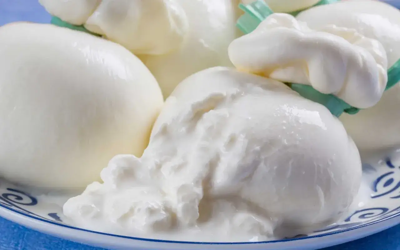 Świeża burrata, co to jest? Delikatny ser z kremowym wnętrzem, podany na talerzu z niebieskim wzorem.
