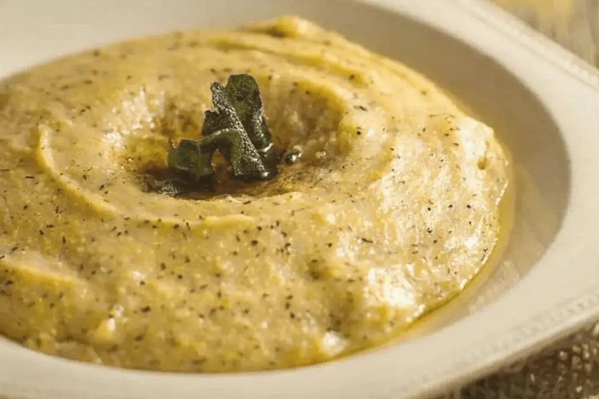 Kremowa polenta bergamo, doprawiona ziołami i pieprzem, podana w białej misce.